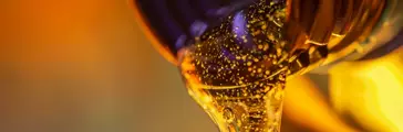 Liquid stream of motor oil flows from the neck of the bottle close-up