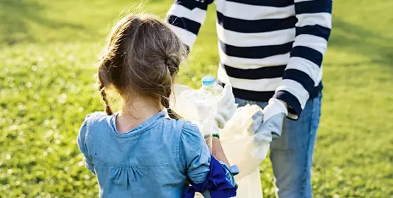 Young girl and mother working together to clean-up trash in the park.