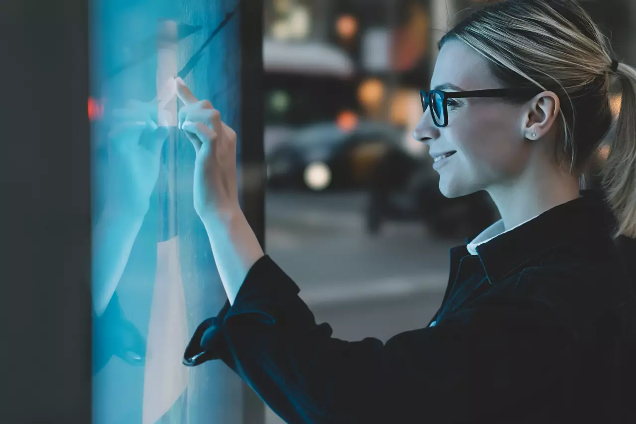 Smiling female touching a big display with advanced digital technology