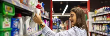 Pretty young woman buying groceries in a supermarket/mall/grocery store. Beautiful brunette looking at some shelves in a supermarket trying to decide what to buy