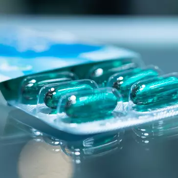 Blue soft gel capsule medicine in strip package with blur background