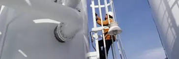 Man climbing ladder at industrial plant 