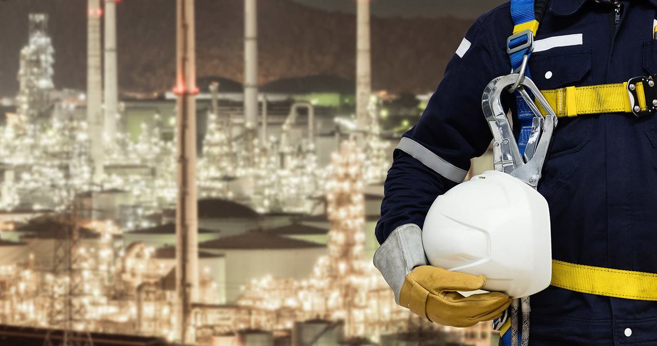 Employee wearing climbing harness holding hard hat