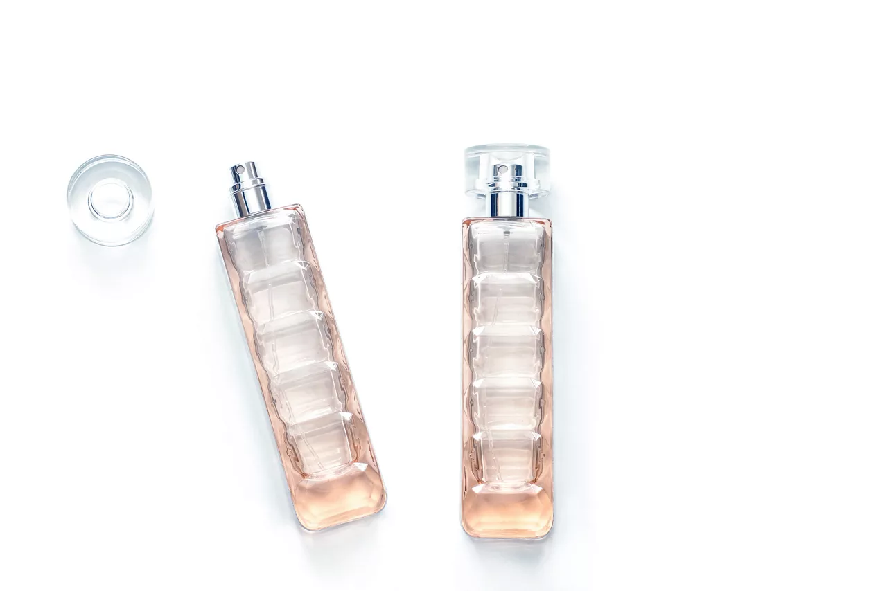 Two perfume bottles, transparent glass spray and bottle cap isolated on white background | K2025 color edit