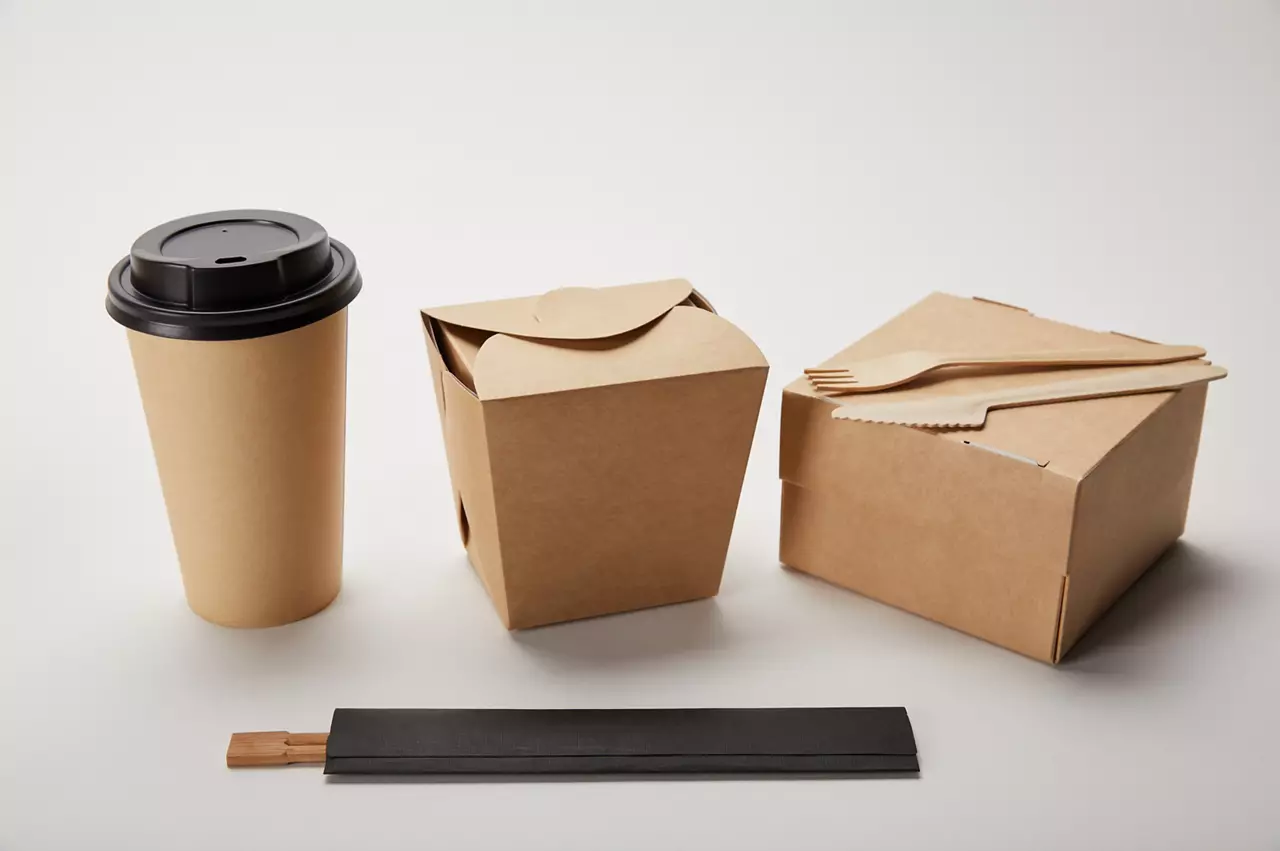 close up view of paper coffee cup, food boxes and chopsticks on white
